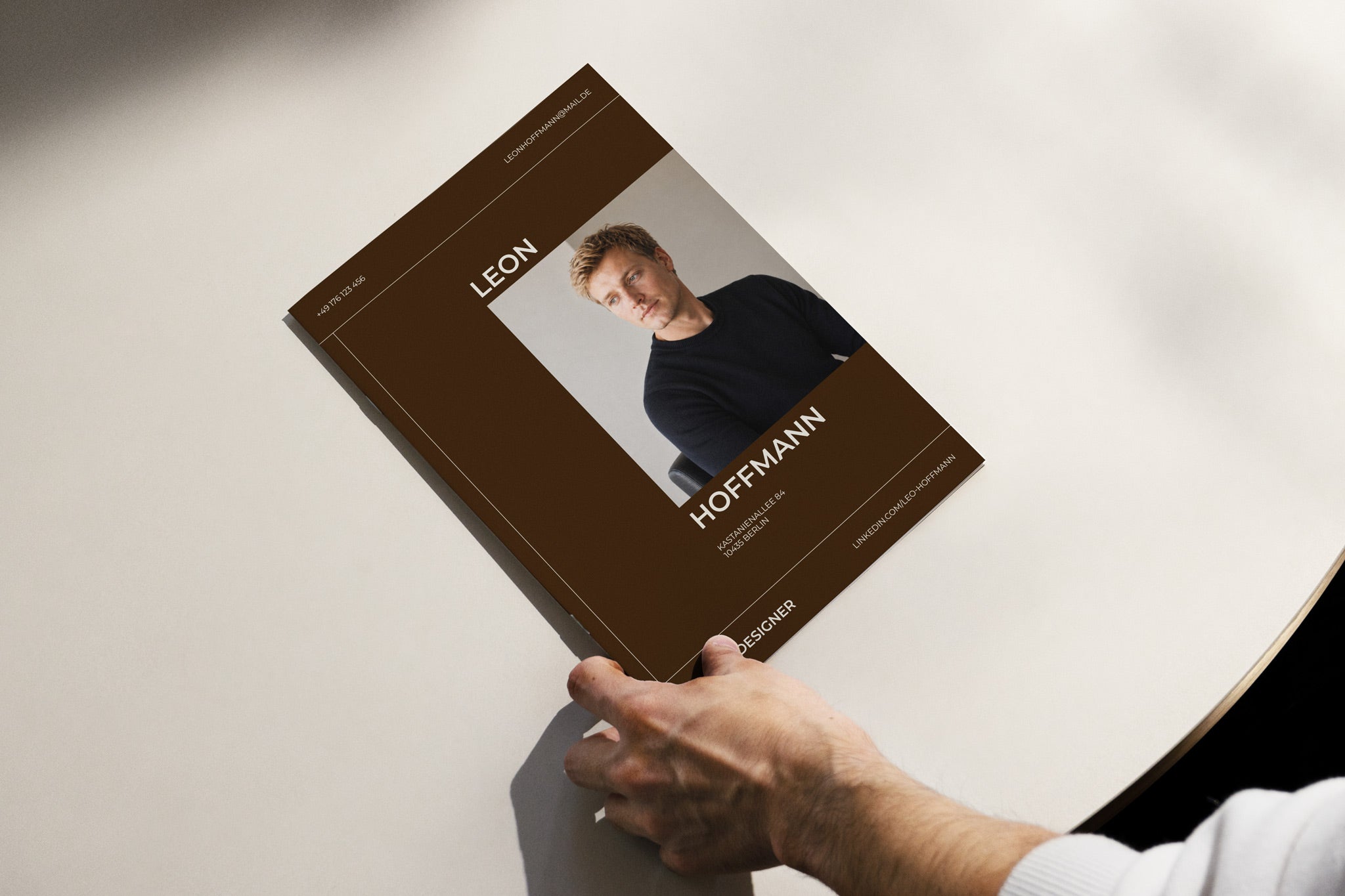 Deckblatt SIENNA Karriere Frontalansicht auf einem weißen Tisch mit Hand